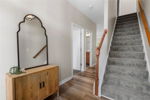 staircase featuring wood finished floors and baseboards