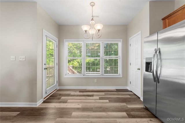 unfurnished dining area with a chandelier, wood finished floors, and baseboards
