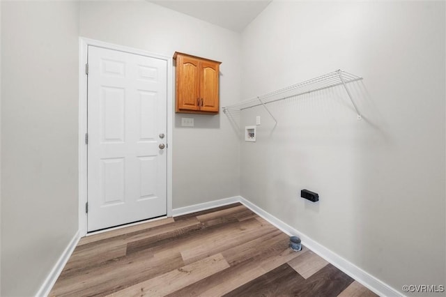 washroom featuring wood finished floors, washer hookup, baseboards, and cabinet space