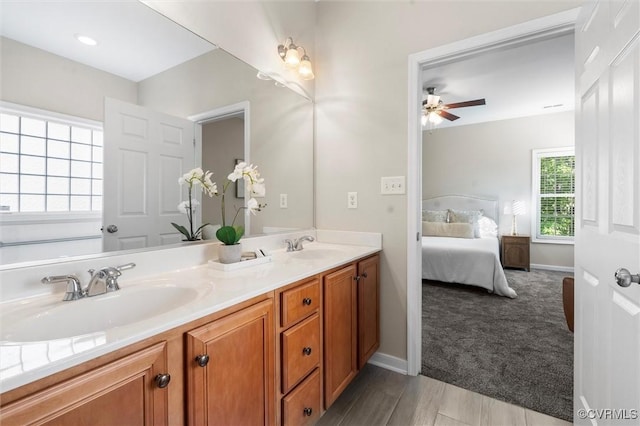 ensuite bathroom featuring a ceiling fan, double vanity, baseboards, and wood finished floors