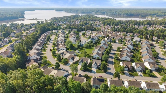 aerial view of property and surrounding area featuring a nearby body of water, nearby suburban area, and a heavily wooded area
