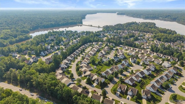 view of property location with a nearby body of water, a forest, and nearby suburban area