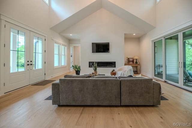 4629 Butte Rd, Richmond, VA 23235 - living area with french doors, light wood-style flooring, a towering ceiling, a glass covered fireplace, and baseboards