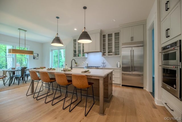 4629 Butte Rd, Richmond, VA 23235 - kitchen featuring appliances with stainless steel finishes, light countertops, a breakfast bar area, light wood-style floors, and an island with sink