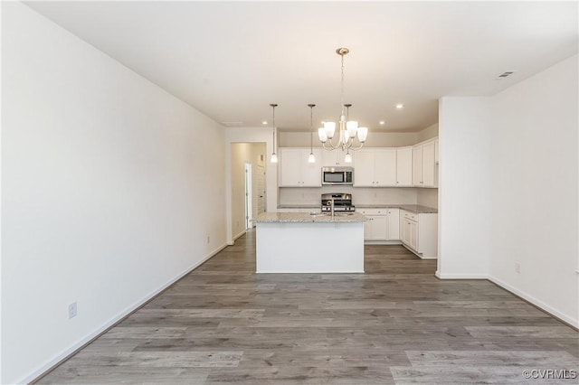 kitchen featuring an inviting chandelier, an island with sink, light wood-type flooring, white cabinetry, and appliances with stainless steel finishes