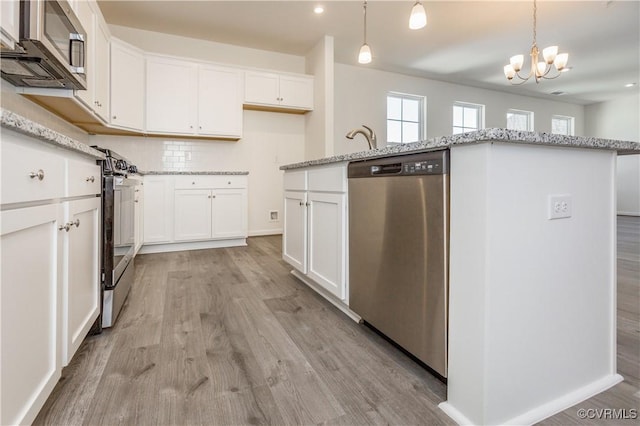 kitchen with a notable chandelier, appliances with stainless steel finishes, light stone counters, white cabinetry, and light wood-type flooring