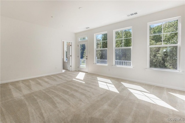 spare room featuring light colored carpet, baseboards, and visible vents