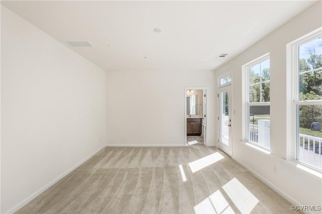 spare room featuring light colored carpet, baseboards, and visible vents