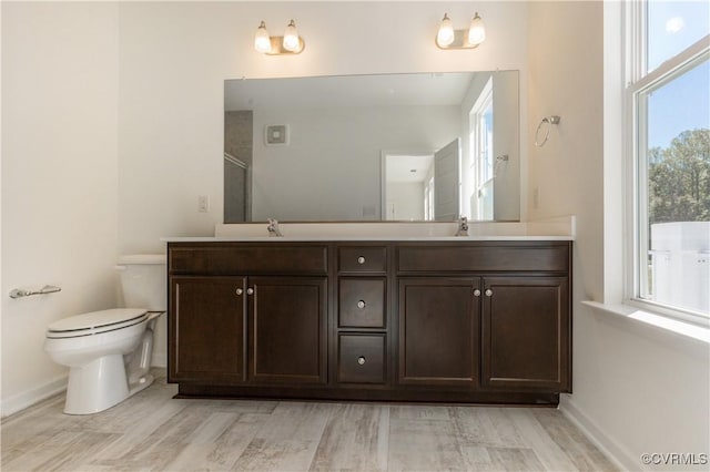 bathroom with a healthy amount of sunlight, baseboards, and toilet
