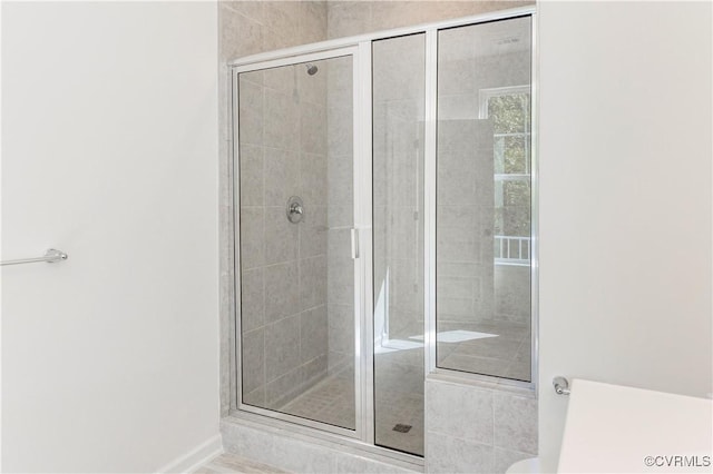 bathroom with baseboards and a shower stall