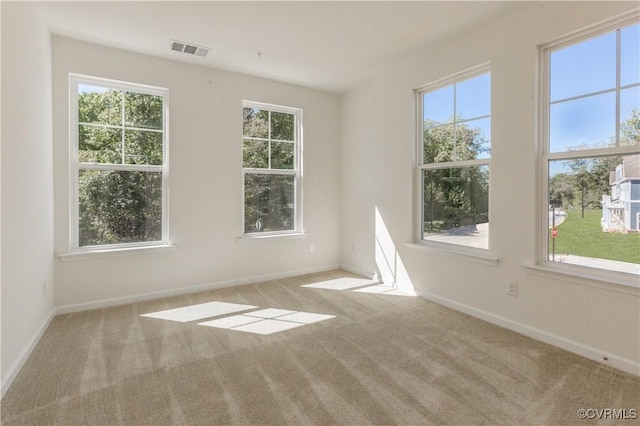 unfurnished room featuring carpet flooring, visible vents, and plenty of natural light
