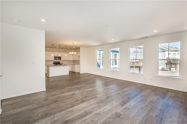 unfurnished living room featuring visible vents, baseboards, dark wood-style floors, a chandelier, and recessed lighting