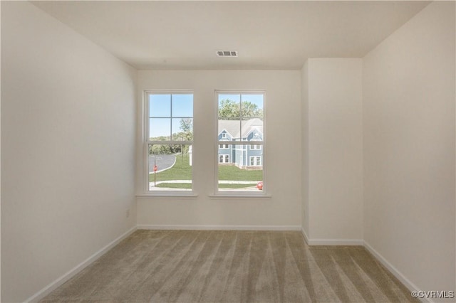 spare room with light colored carpet, baseboards, and visible vents