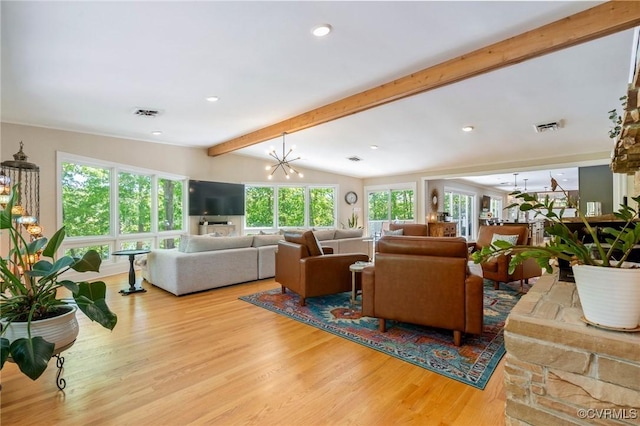 living area with a healthy amount of sunlight, lofted ceiling with beams, wood finished floors, and visible vents