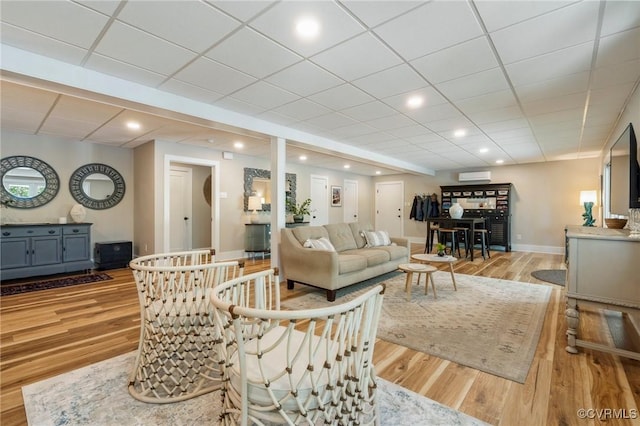 living area featuring recessed lighting, baseboards, a drop ceiling, and light wood-style floors