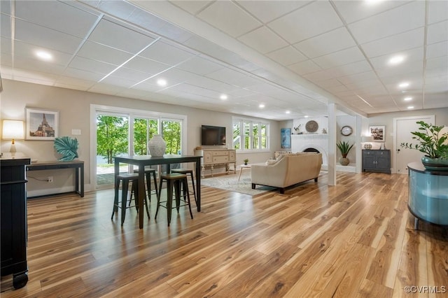 dining area featuring a paneled ceiling, a fireplace, wood finished floors, baseboards, and recessed lighting