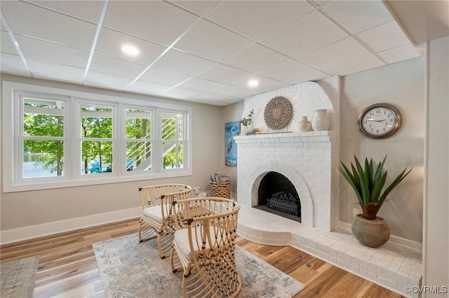 living area with a brick fireplace, recessed lighting, baseboards, and wood finished floors