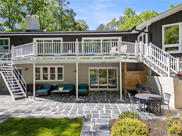 back of property with an outdoor hangout area, a wooden deck, board and batten siding, stairway, and a patio area