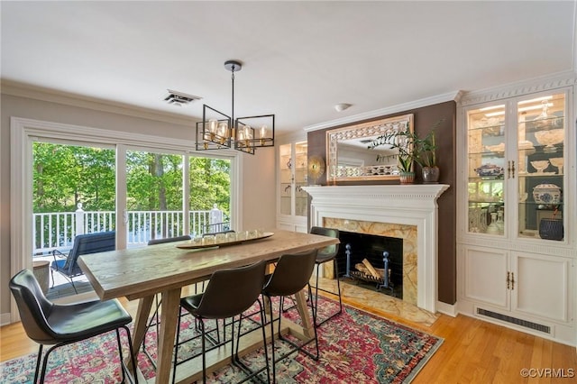 dining room with a notable chandelier, visible vents, ornamental molding, and a high end fireplace