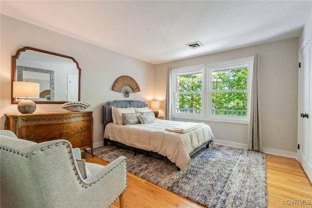 bedroom featuring baseboards, wood finished floors, and visible vents