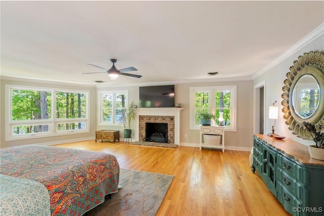 bedroom featuring a brick fireplace, light wood-style flooring, baseboards, visible vents, and ornamental molding