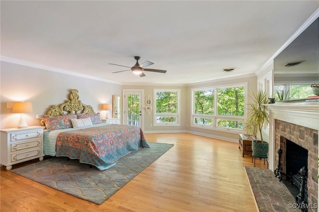 bedroom featuring access to outside, ceiling fan, a fireplace, wood finished floors, and ornamental molding