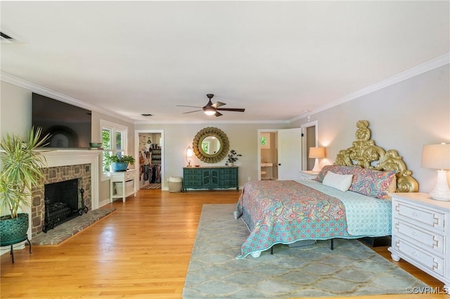 bedroom with crown molding, a fireplace with raised hearth, visible vents, and light wood-type flooring