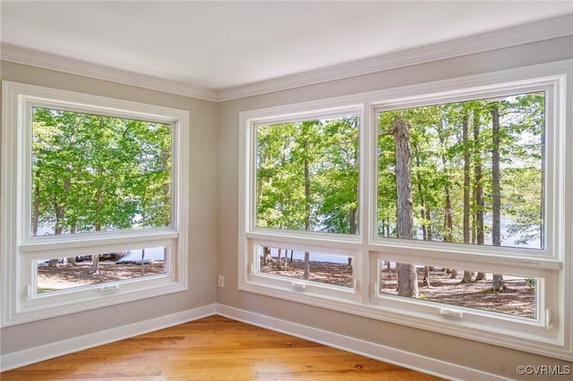 interior space featuring baseboards, ornamental molding, and light wood-style floors