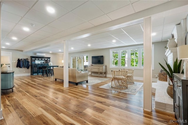 living room with baseboards, a drop ceiling, and light wood finished floors