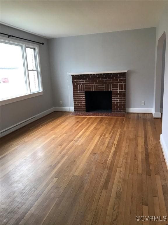 unfurnished living room featuring baseboards, a fireplace, a baseboard heating unit, and hardwood / wood-style flooring