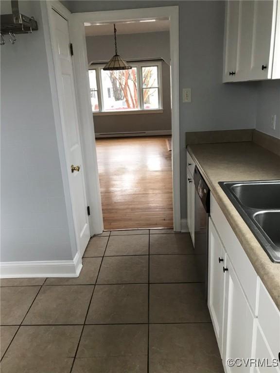 kitchen featuring baseboards, light tile patterned floors, and white cabinets