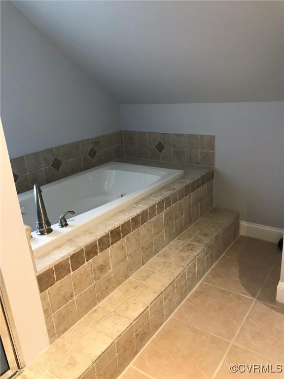 full bath featuring tile patterned floors, lofted ceiling, and a bath