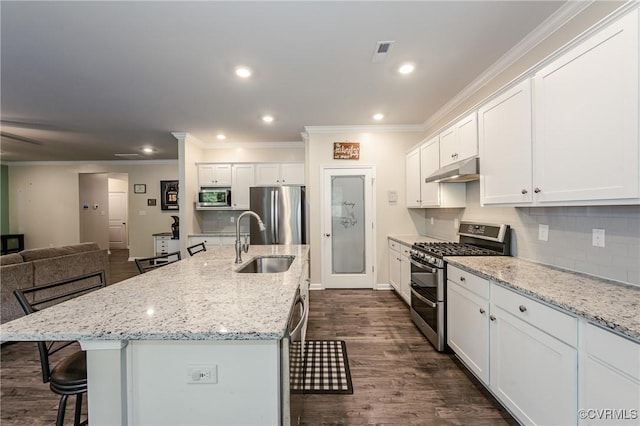 7585 Sedge Dr, New Kent, VA 23124 - kitchen featuring stainless steel appliances, a breakfast bar, under cabinet range hood, ornamental molding, and white cabinetry