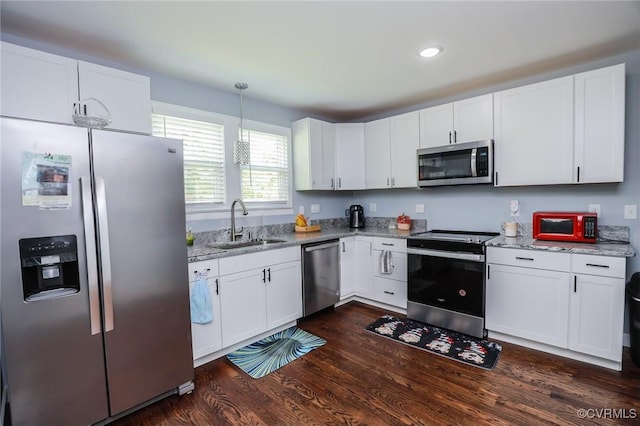 kitchen featuring light stone countertops, white cabinets, a sink, dark wood finished floors, and stainless steel appliances