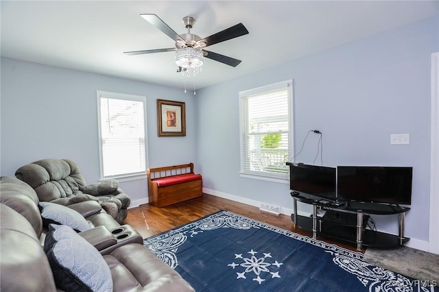 living area with baseboards, a ceiling fan, wood finished floors, and visible vents