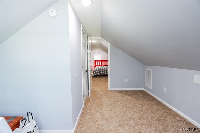 additional living space featuring baseboards, light carpet, vaulted ceiling, and visible vents