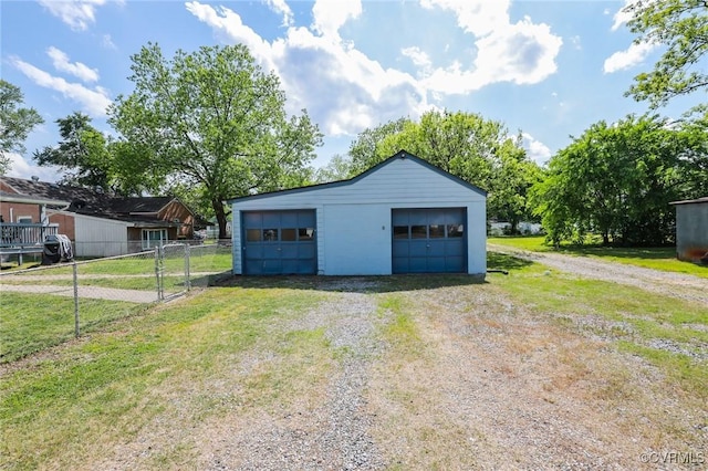 detached garage featuring fence and driveway