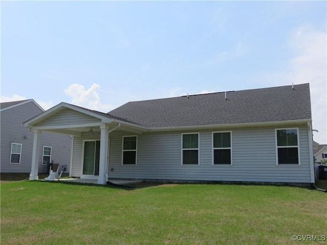 back of property featuring roof with shingles and a yard