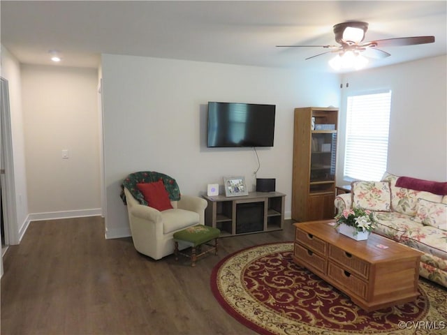 living area featuring a ceiling fan, baseboards, and wood finished floors