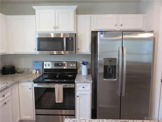 kitchen with stainless steel appliances, light stone counters, and white cabinetry