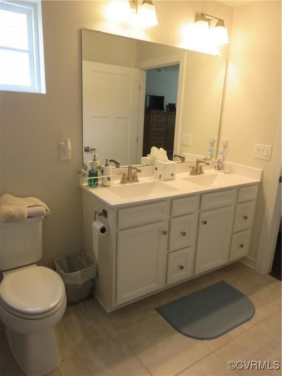 bathroom with a sink, tile patterned floors, toilet, and double vanity