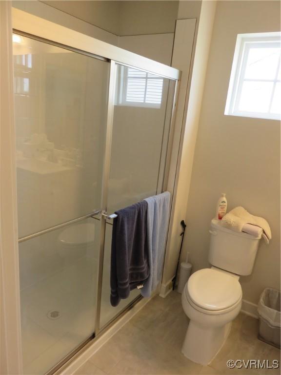 full bath with toilet, a shower stall, and a healthy amount of sunlight