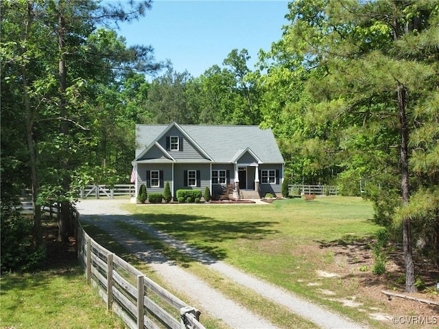 view of front of house with fence, a front yard, dirt driveway, a porch, and a view of trees