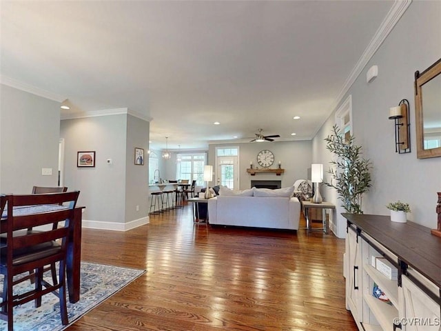 living room with crown molding, a fireplace, ceiling fan, dark wood-type flooring, and recessed lighting