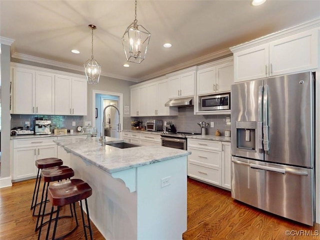 kitchen with ornamental molding, a kitchen island with sink, recessed lighting, appliances with stainless steel finishes, and backsplash
