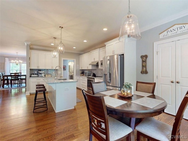 dining room with crown molding, wood finished floors, a toaster, recessed lighting, and a chandelier