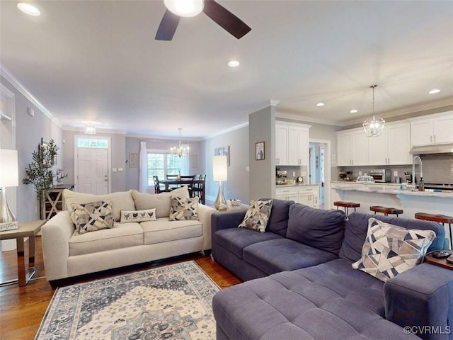 living area with crown molding, recessed lighting, ceiling fan with notable chandelier, and dark wood-style floors