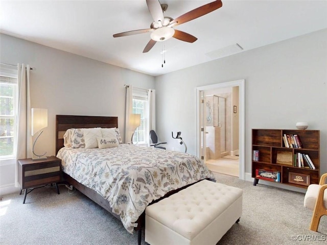 carpeted bedroom with baseboards, connected bathroom, and ceiling fan