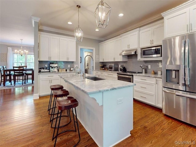 kitchen with an inviting chandelier, crown molding, under cabinet range hood, backsplash, and stainless steel appliances
