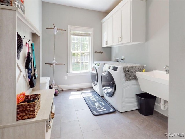 laundry area featuring washing machine and dryer, light tile patterned flooring, baseboards, a sink, and cabinet space